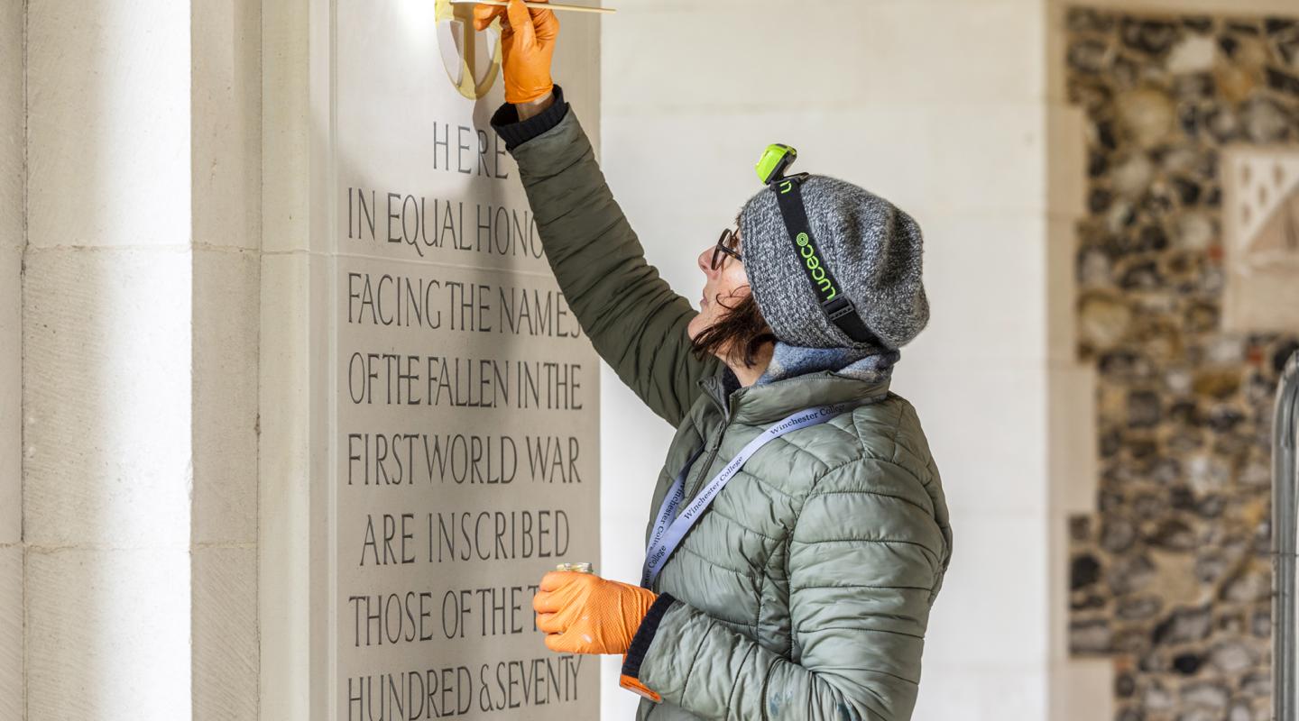 Woman painting inscriptions on building 