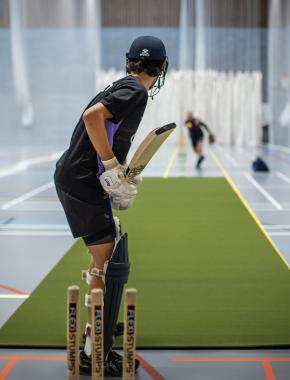 School boy playing cricket indoor hall