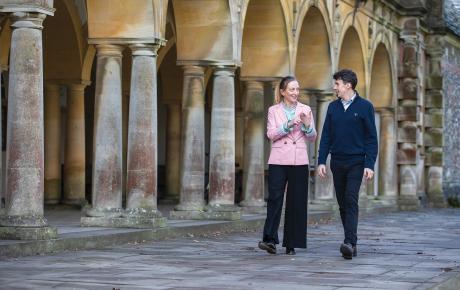 Emma Macey and Jack Andrews walking along chatting, in front of University of Oxford architecture