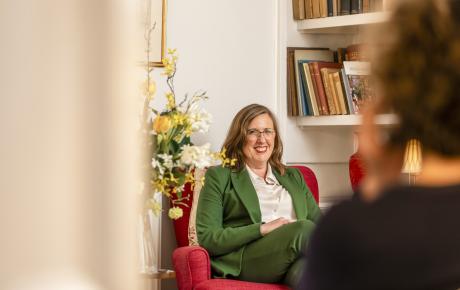 Woman sat on armchair wearing a green suit