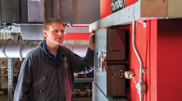 Man standing next to red boiler