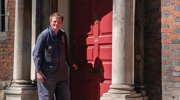 Man standing outside boarding house with a red front door