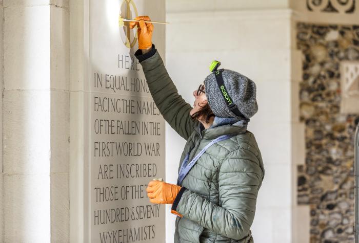 Woman painting inscriptions on building 