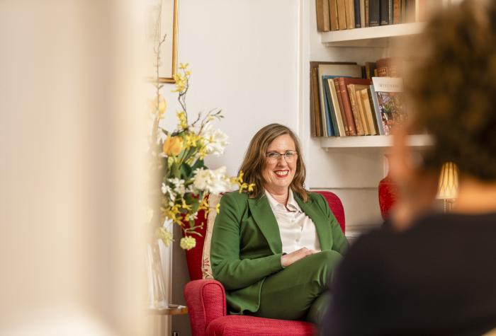 Woman sat on armchair wearing a green suit