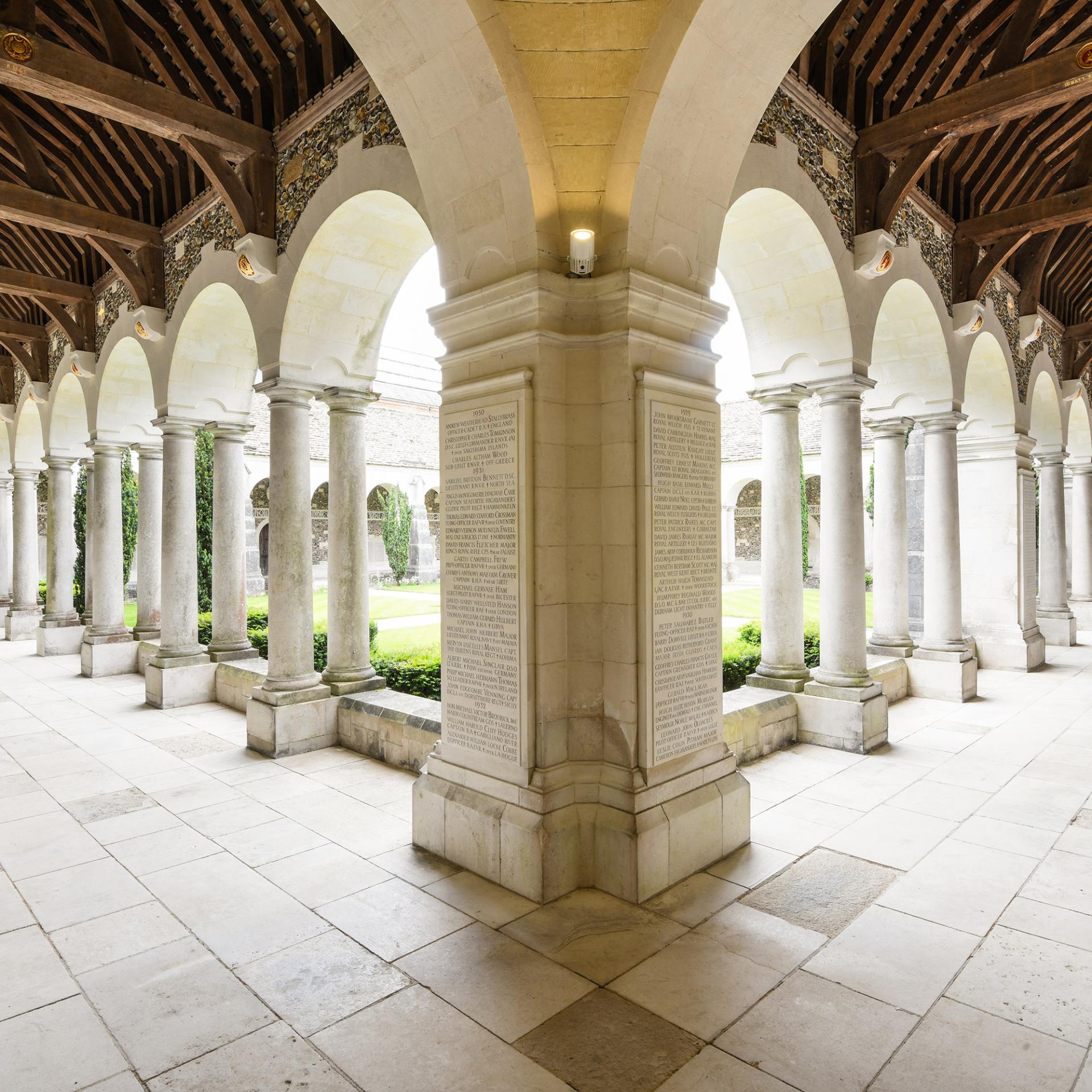 View looking down the historic arches of the war cloisters, with a stone floor. 